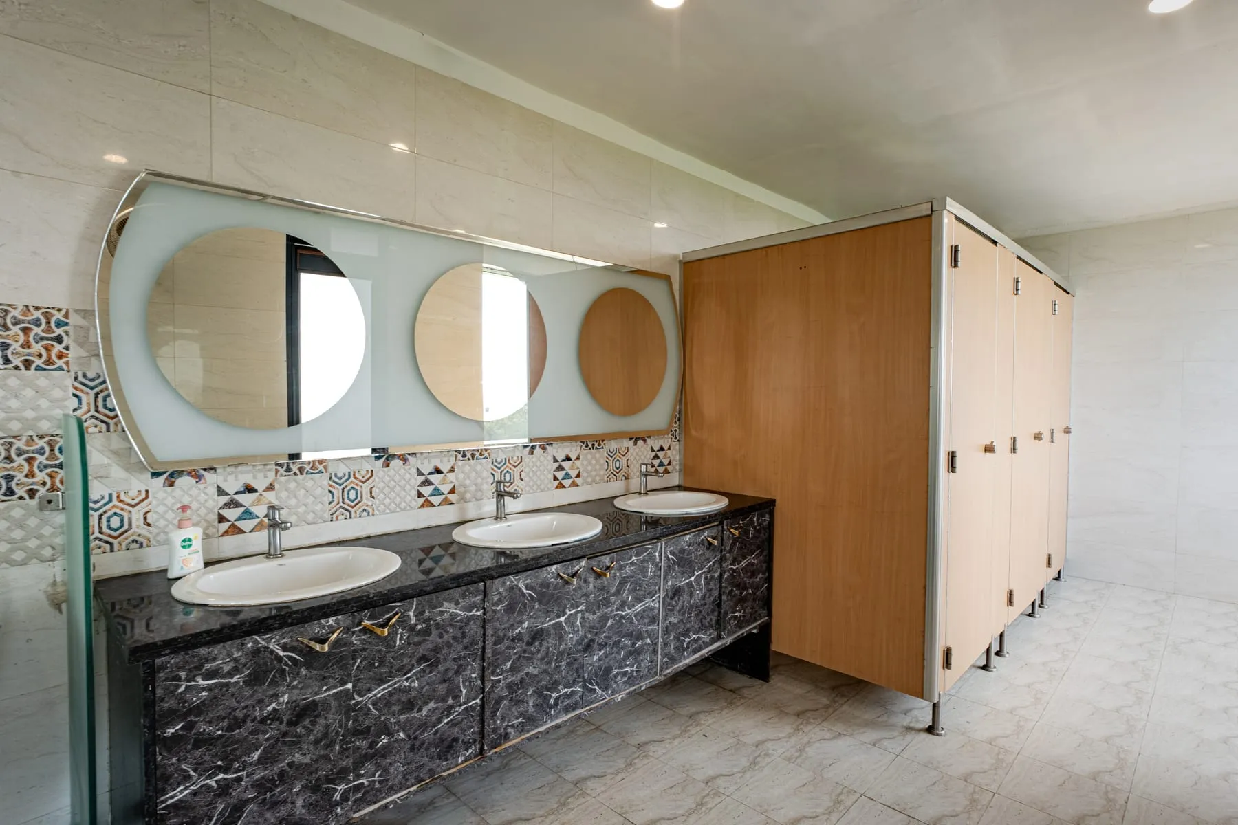 Office-floor washroom with vanity and round mirrors